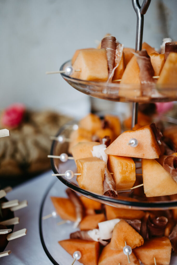 Fingerfood-Etagere mit Melonenstücken und Schinken am Spieß