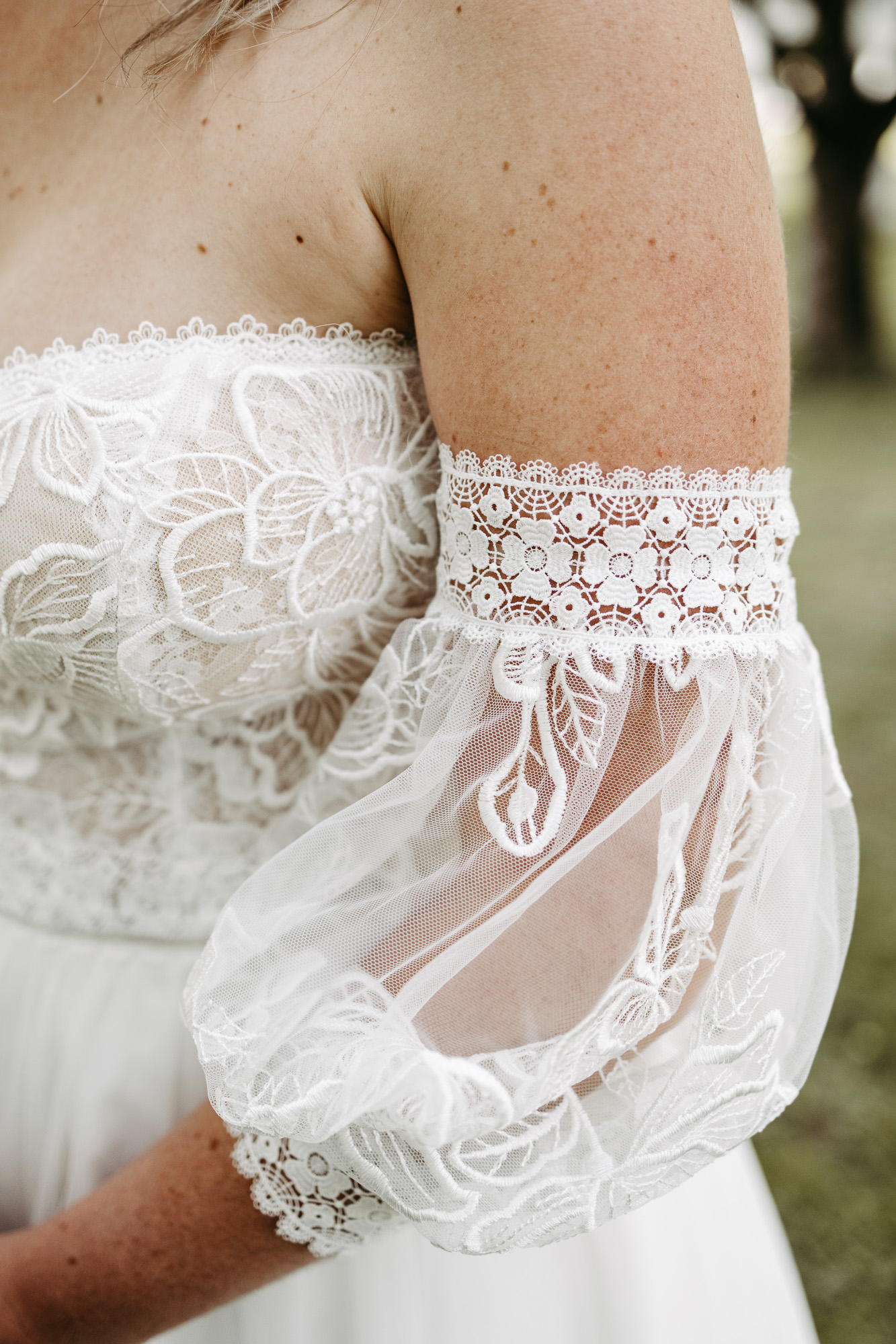 Detail: Spitzenärmel des Brautkleids mit transparentem Tüll auf der Schulter