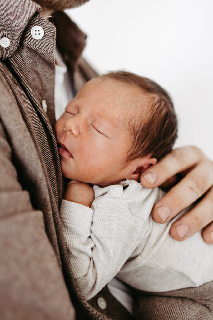 Neugeborenes schläft auf der Schulter des Vaters, Nahaufnahme des Gesichts, Newborn-Shooting im Fotostudio Freistadt