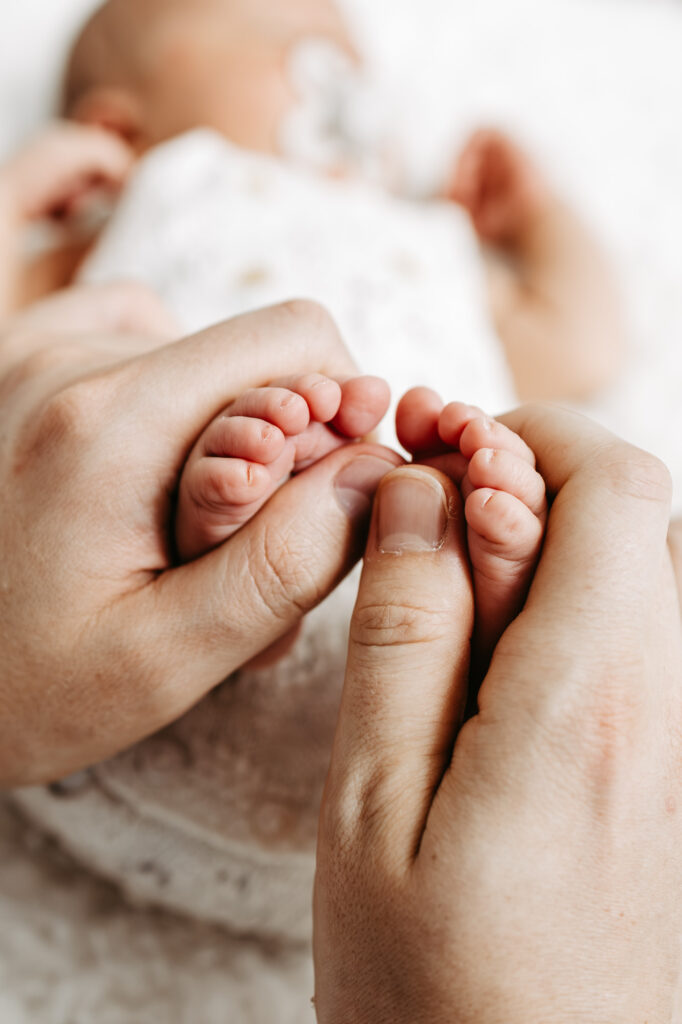 Nahaufnahme der kleinen Babyfüßchen, sanft von den Händen der Eltern umschlossen