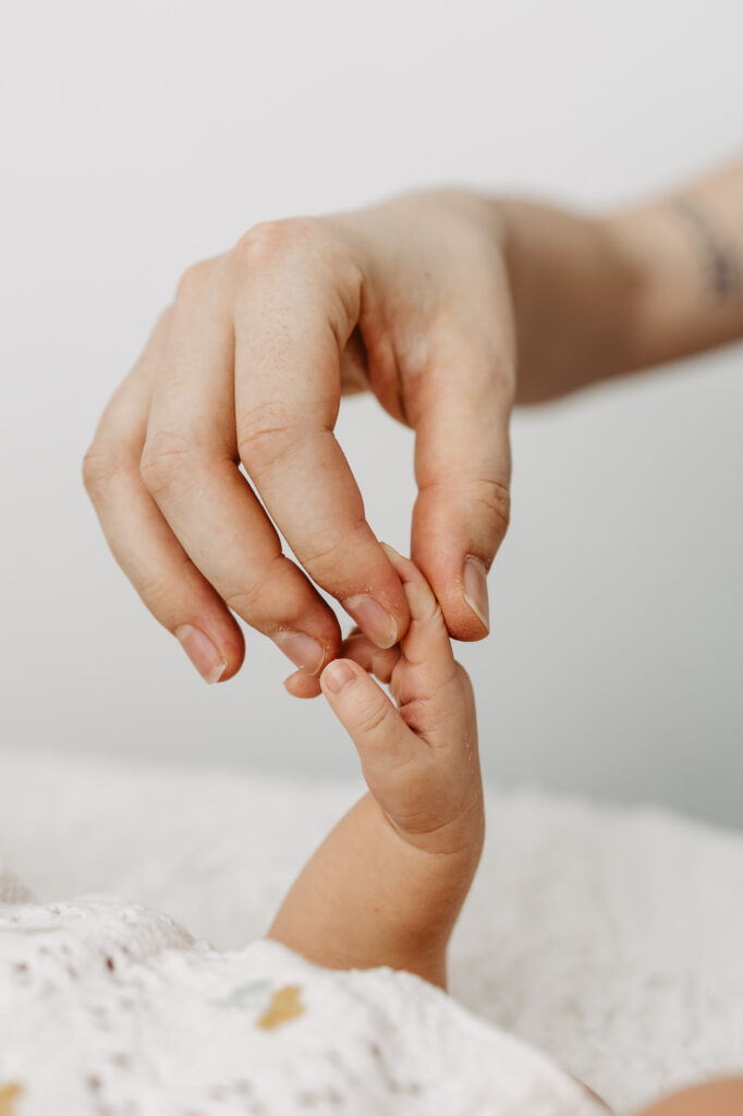 Nahaufnahme: das kleine Händchen des Babys hält den Finger der Mutter fest