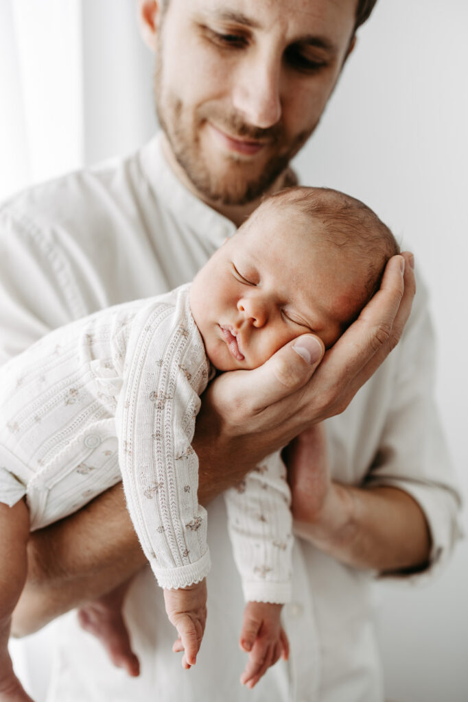 Detailaufnahme: das schlafende Babygesicht ruht in der Hand des Vaters