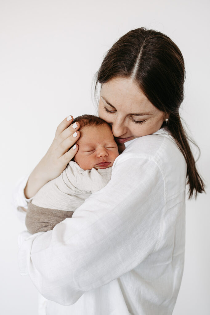 Mutter kuschelt ihre Nase an den Kopf des schlafenden Babys