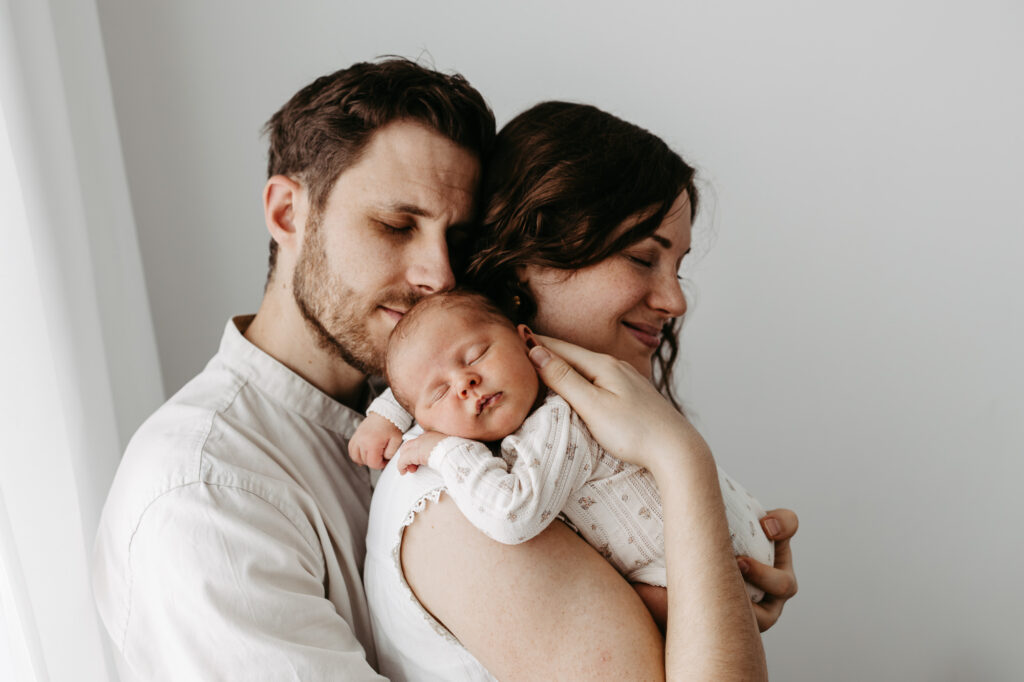 Schwarz-weiß-Aufnahme: Vater hält lächelnd sein Baby in der Hand