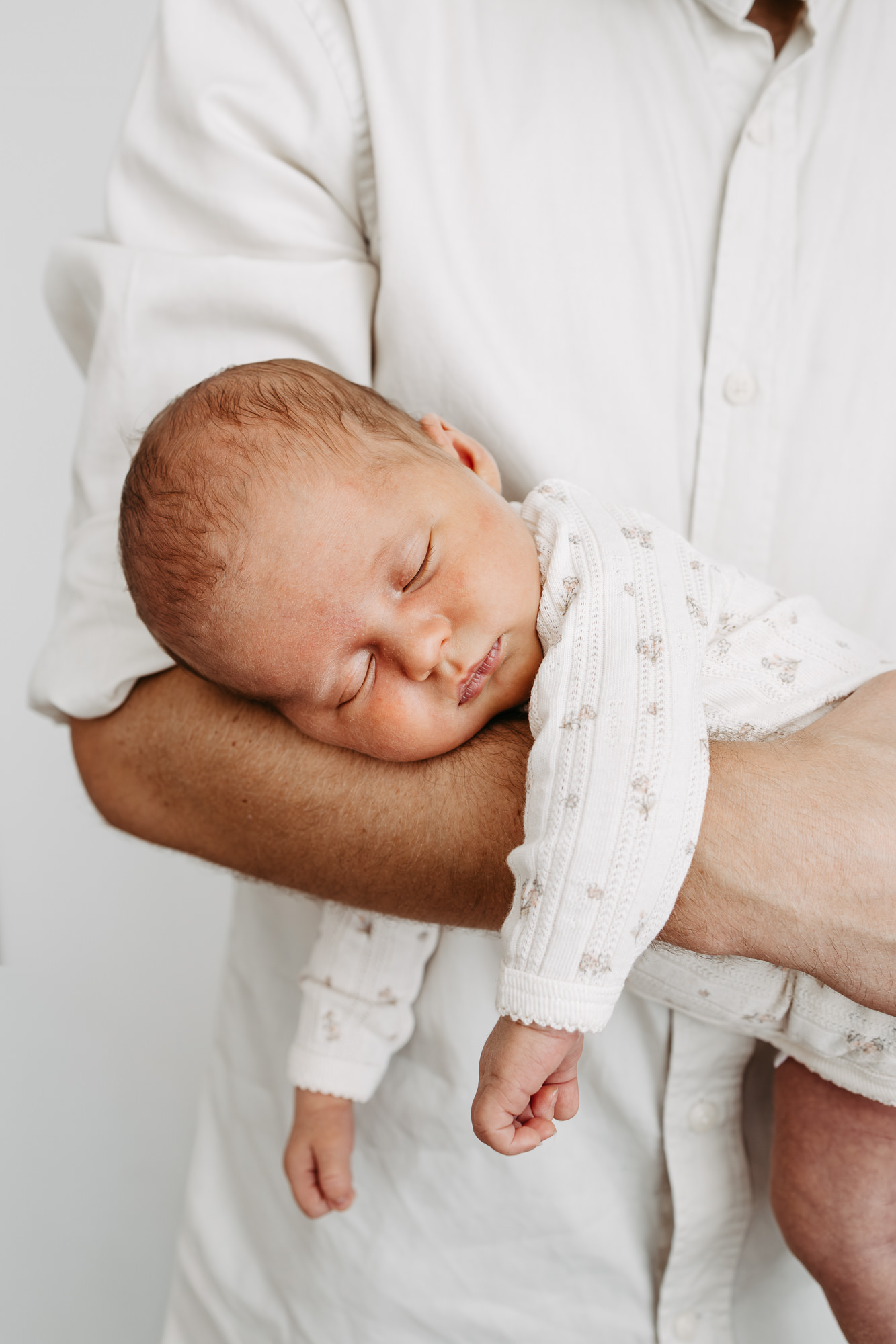 Vater hält sein schlafendes Neugeborenes stehend im Arm, Nahaufnahme