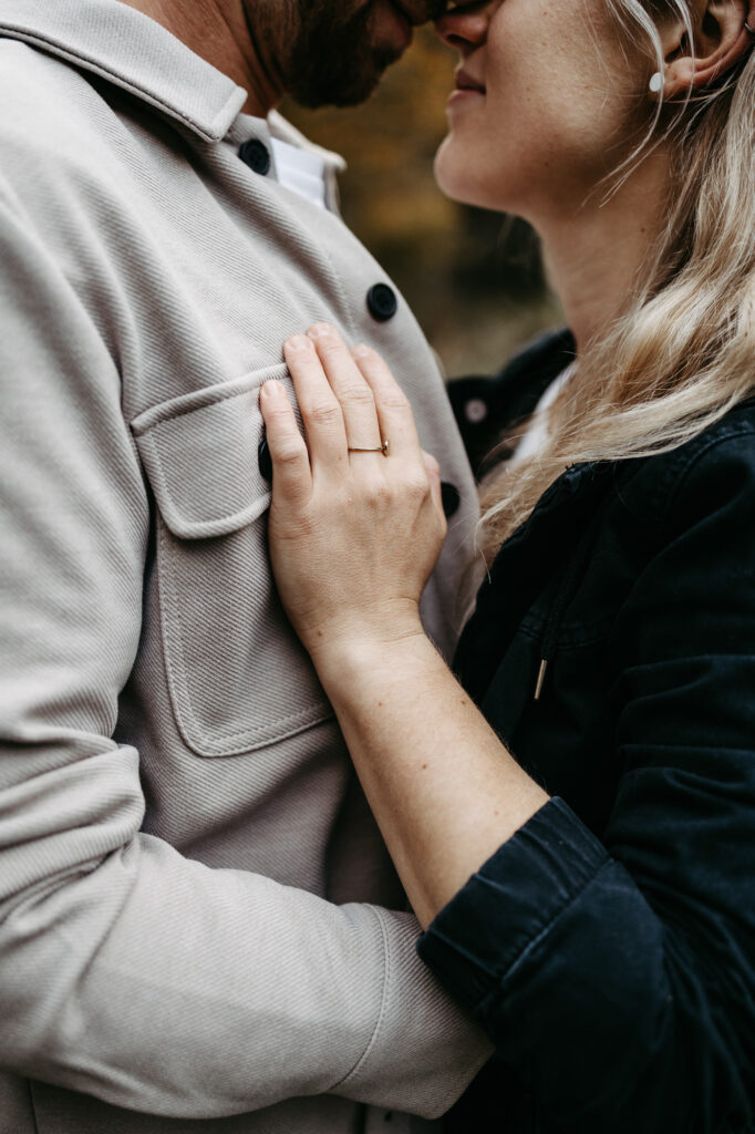 Detail: Hände nah beieinander, Gesichter des Paares im Hintergrund erkennbar